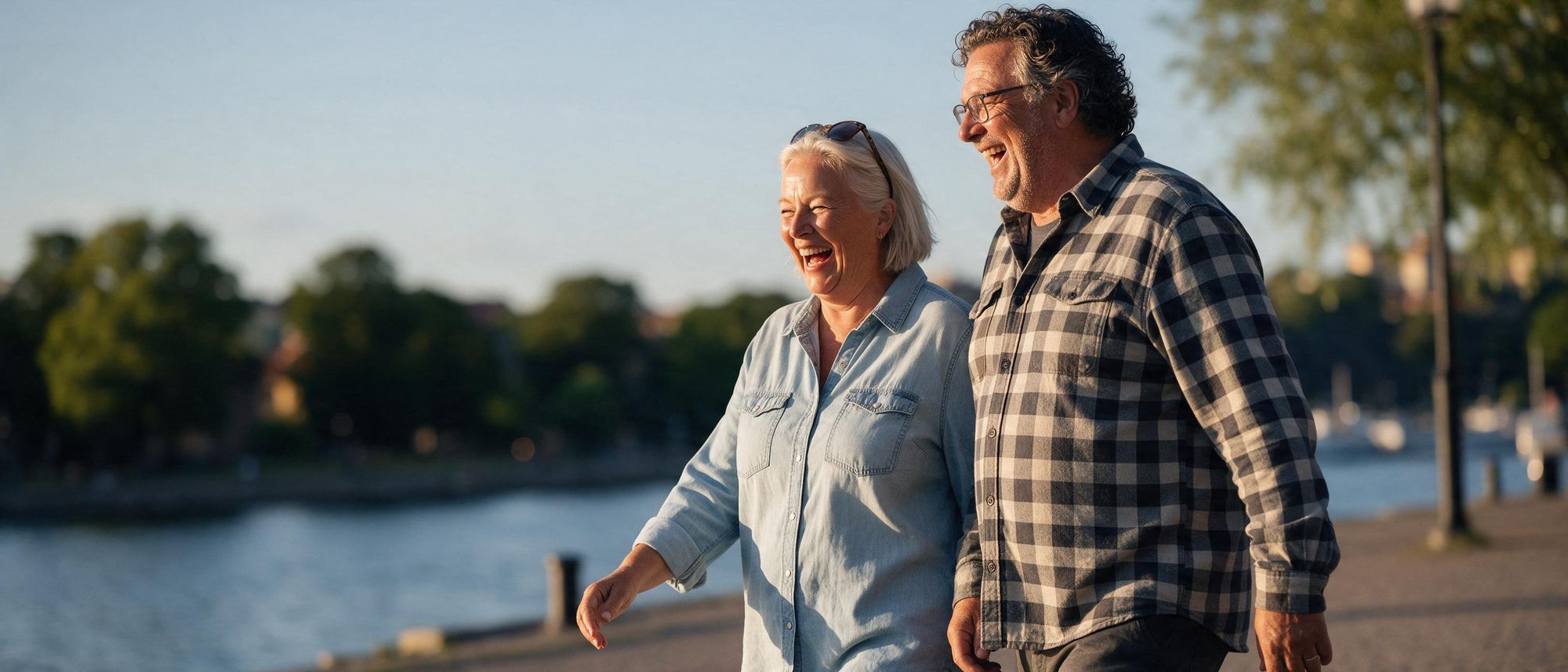 Par som promenerar längs vattnet i kvällssolen och skrattar
